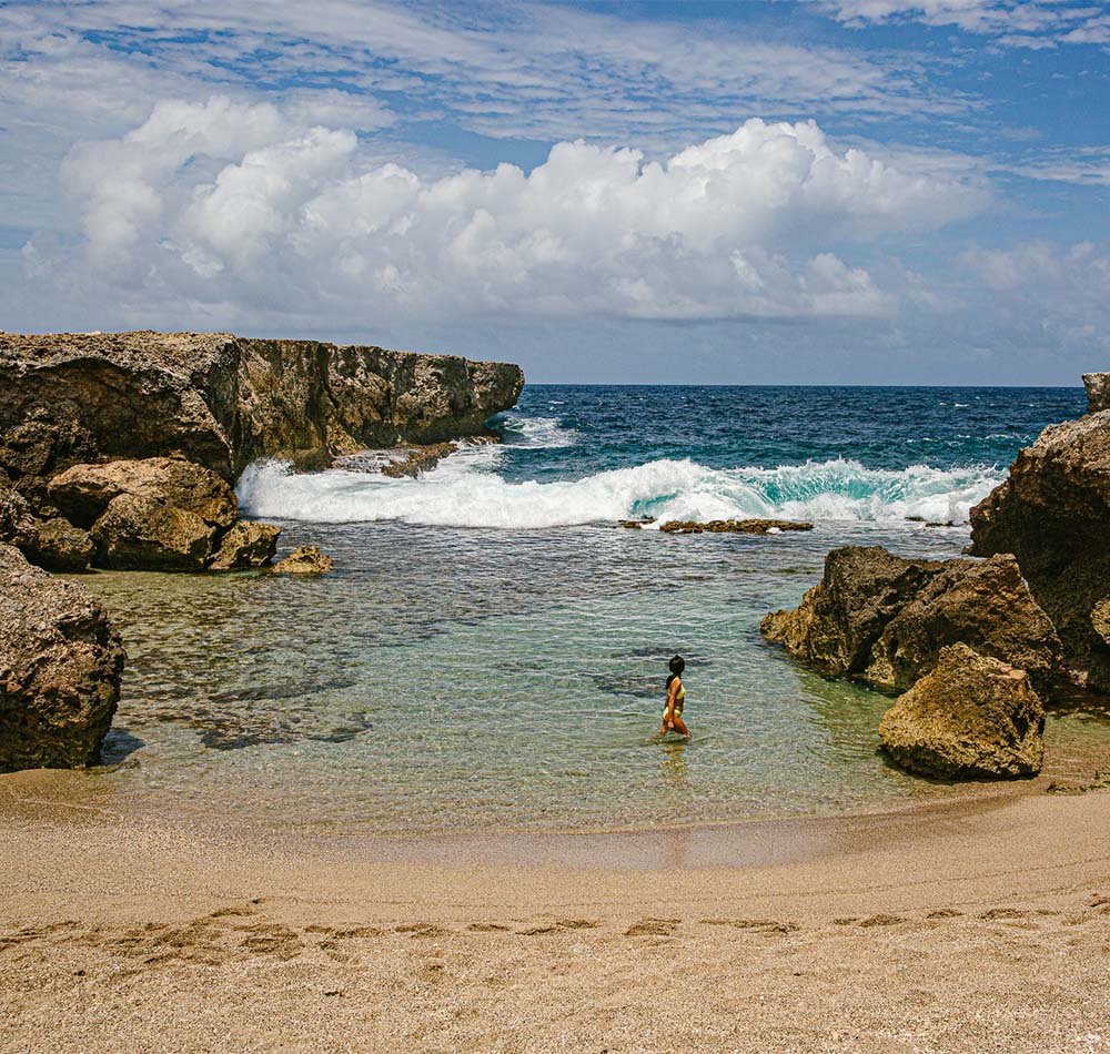 Women standing in ocean water surrounded by beach rocks