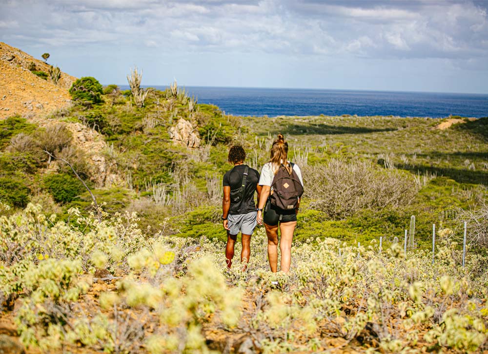 Male and female hikers enjoying the scenic landscape of Washington Slagbaai National Park.