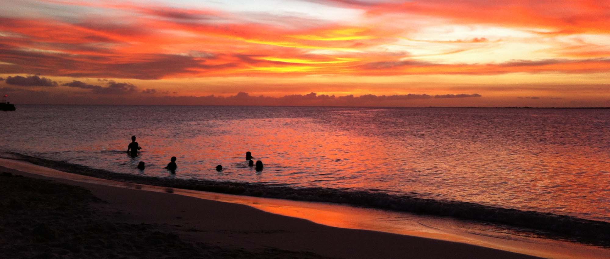 People swimming in the ocean during sunset