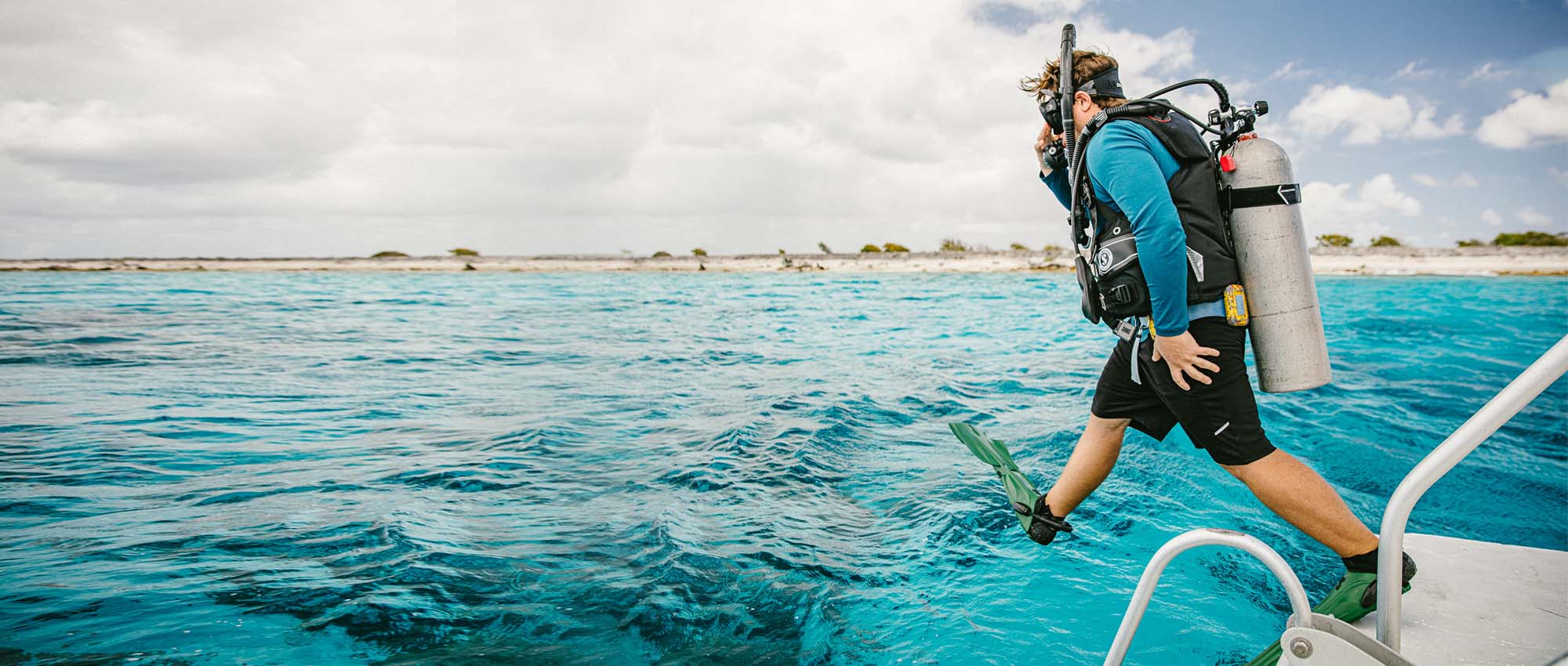 Man jumping into the water wearing scuba diving gear