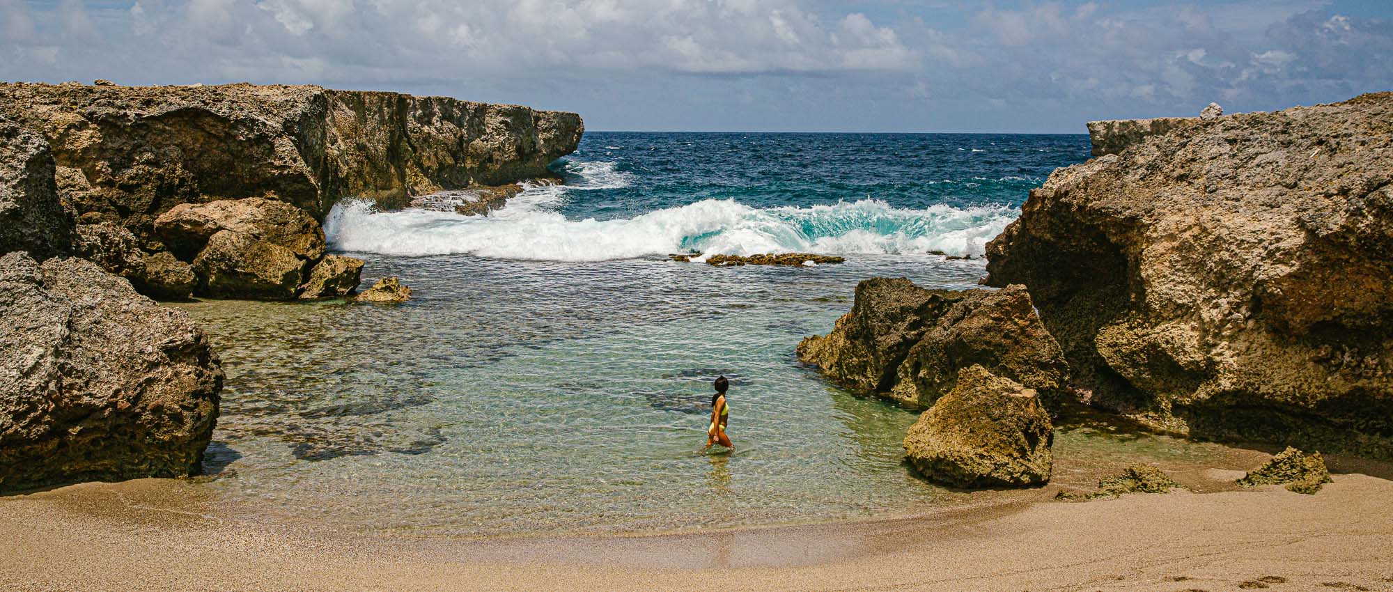 Women standing in ocean water surrounded by rocks