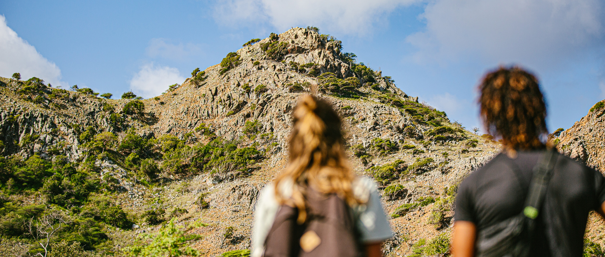 Male and female hikers staring up at mountain