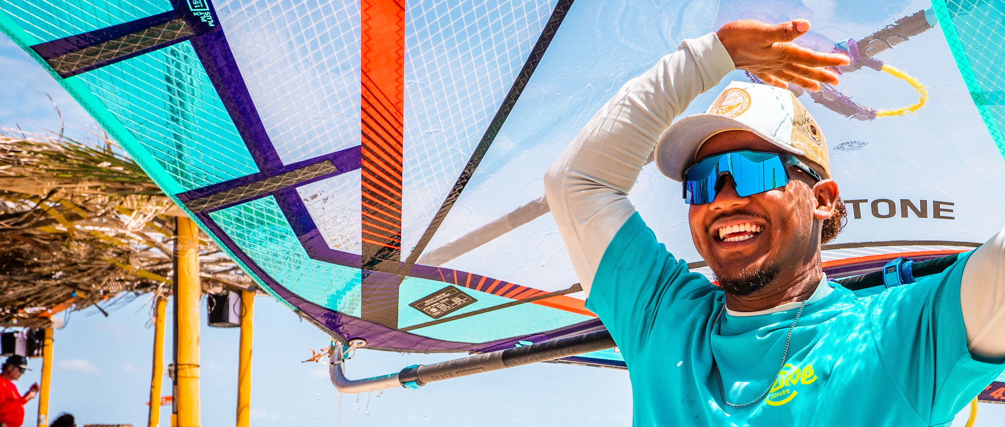 Local Bonarian smiling and holding a windsurf above his head